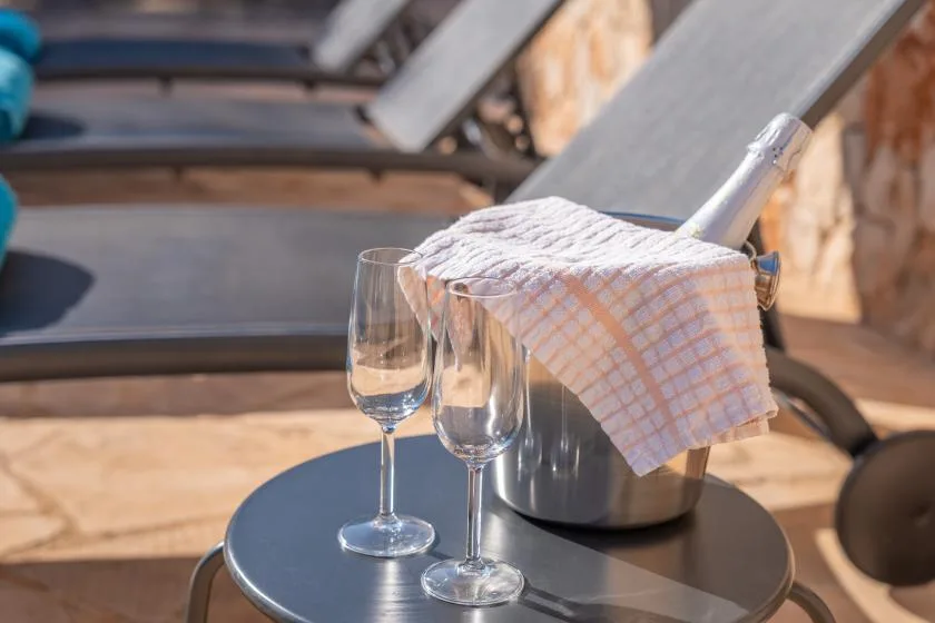 A small outdoor table holds two glasses and a metal bucket covered with a checked cloth.