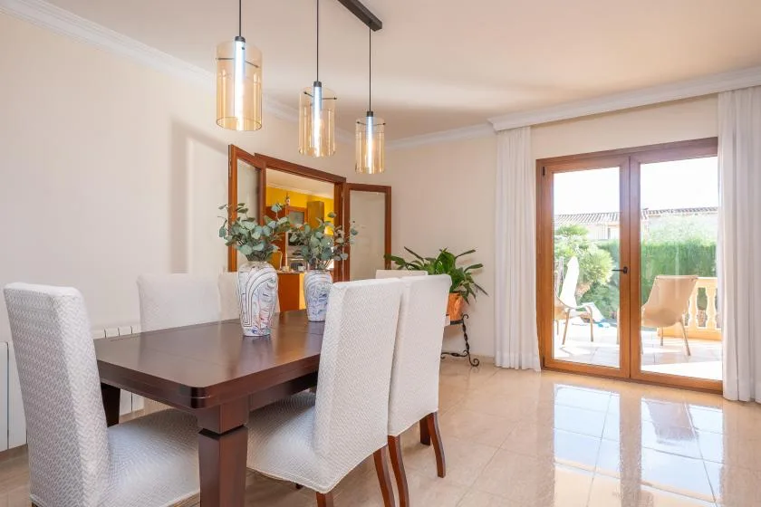 A dining area with a dark table, upholstered seating, and glass doors opening onto a patio.