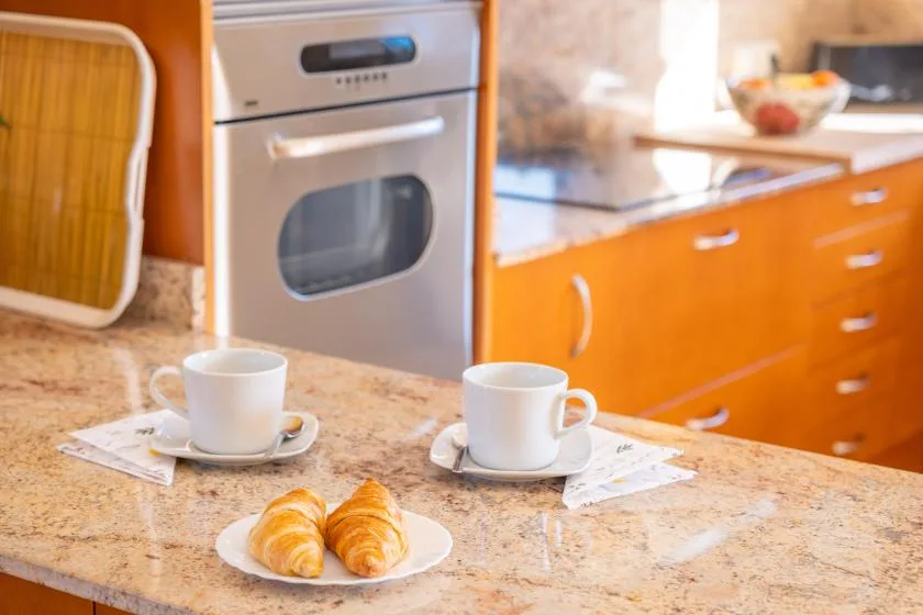 A kitchen counter with cups and pastries beside an oven.