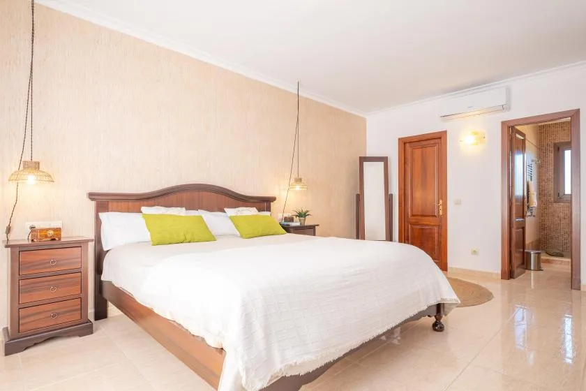 A bedroom with a large bed, bedside tables, and an open doorway.