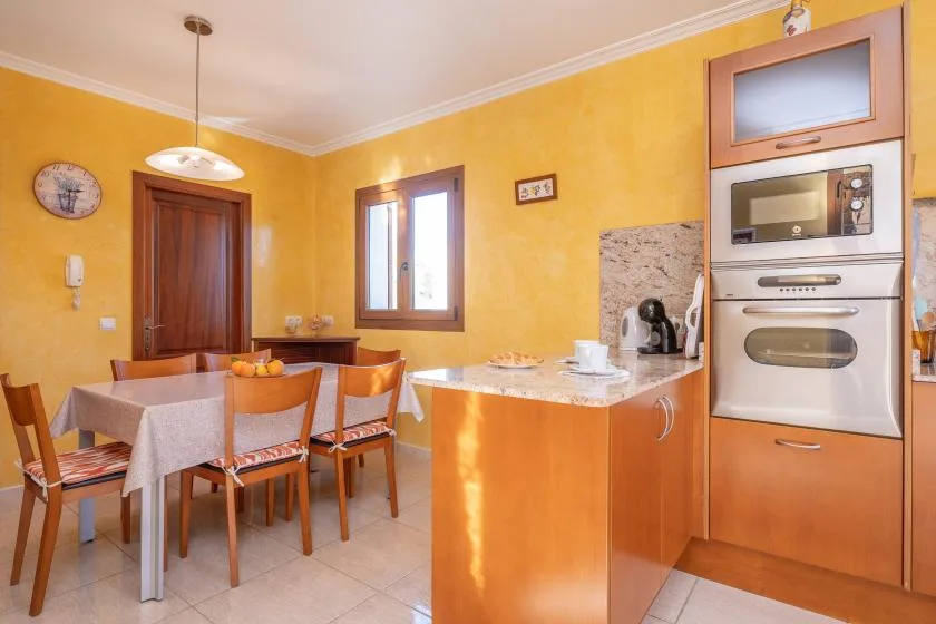 A yellow-walled kitchen with a dining table and a central counter.