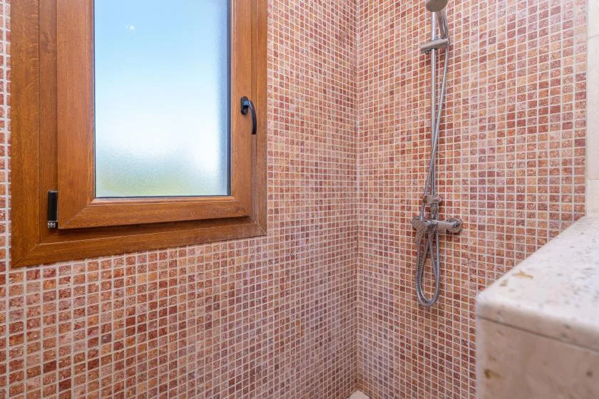 A tiled shower area with a frosted window and wall-mounted shower fixtures.