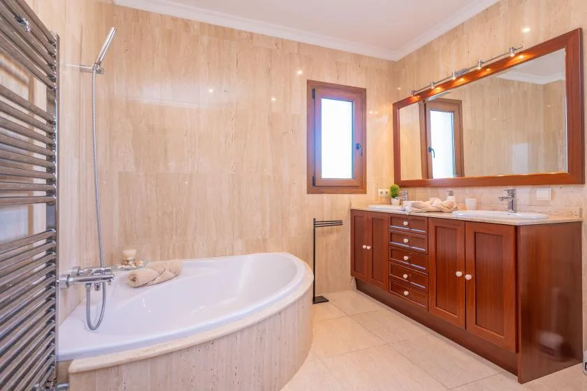 A bathroom with a bathtub and a wooden vanity beneath a large mirror.