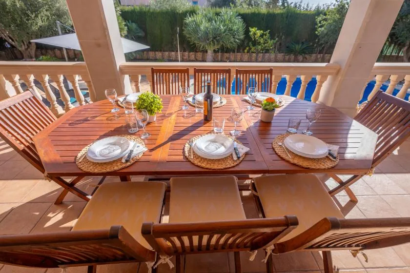 A covered outdoor dining area with a set wooden table and chairs.