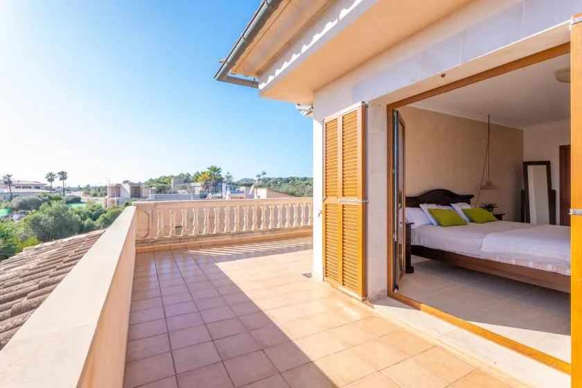 A tiled outdoor terrace opens onto a bedroom through wide sliding doors.