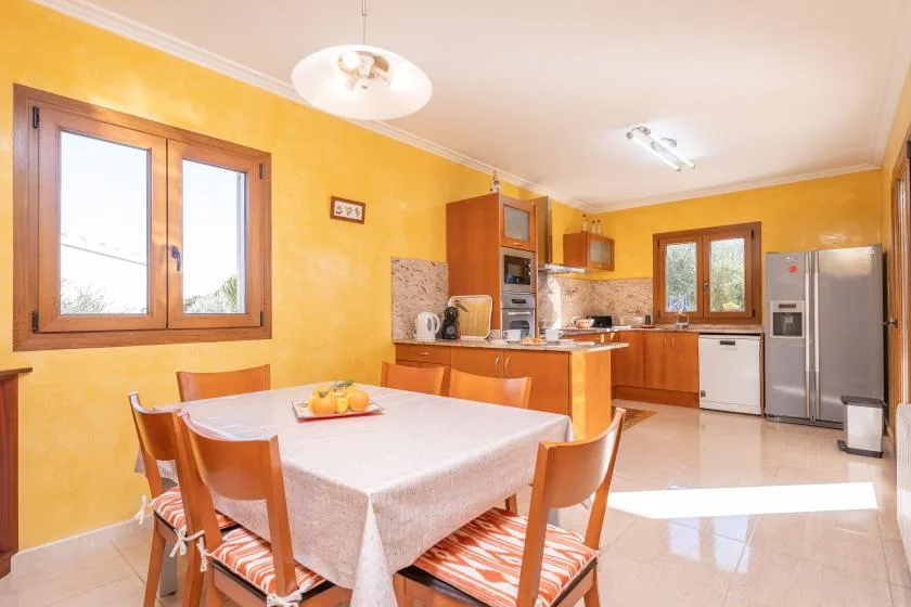 A dining area with a table and chairs sits beside a bright kitchen.