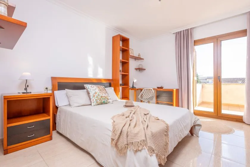 A bedroom with a bed, wooden shelving, and glass doors opening to a balcony.