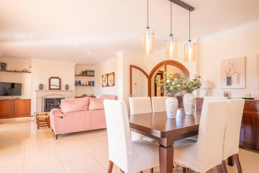 A bright living and dining room with a pink sofa and a dining table.