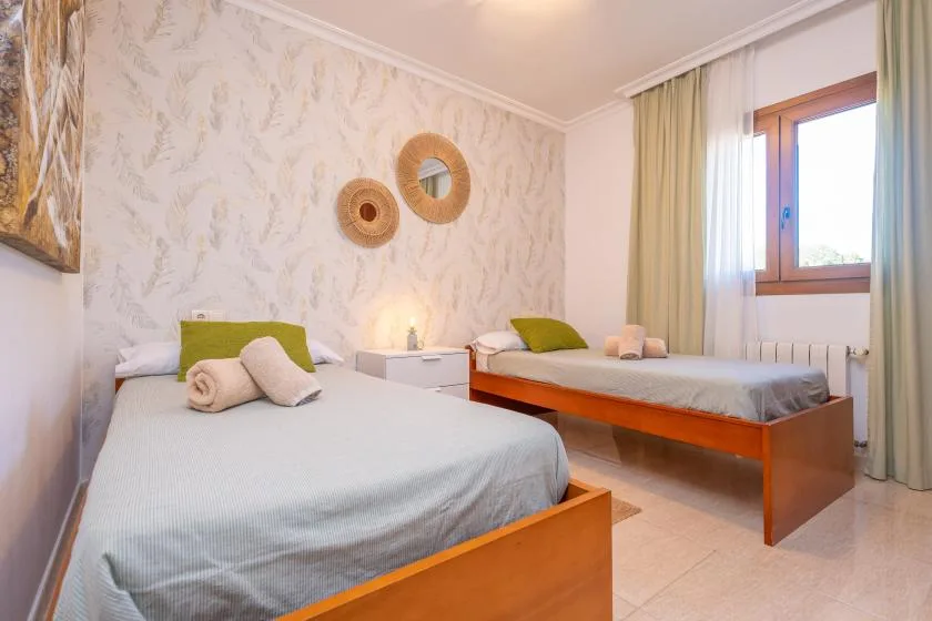 A bright bedroom with two beds and a large window.