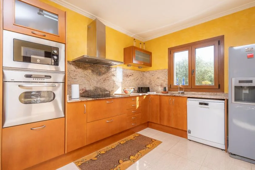 A bright kitchen with wooden cabinets, a countertop, and a window.