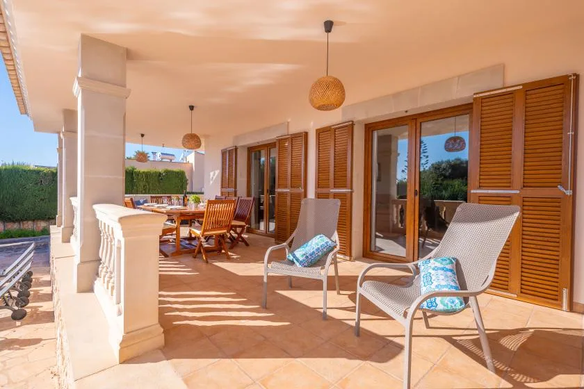 A covered patio with seating and wooden shutters along the wall.