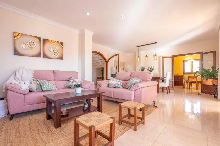 Living room with pink seating, a coffee table, and an open dining area.