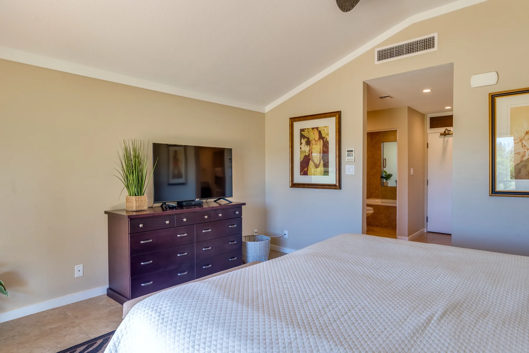 Un dormitorio con una cama, un televisor sobre una cómoda y una puerta abierta.