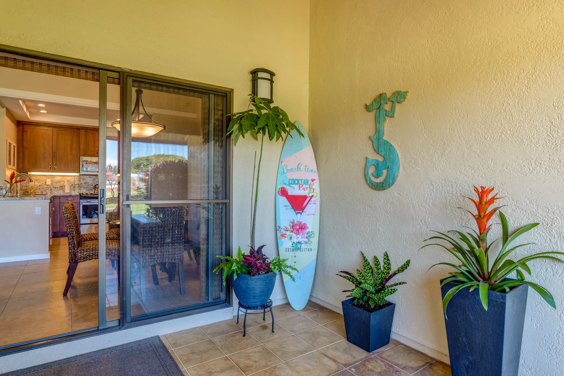 Un patio con plantas en macetas y una puerta corrediza de vidrio que da a una cocina.