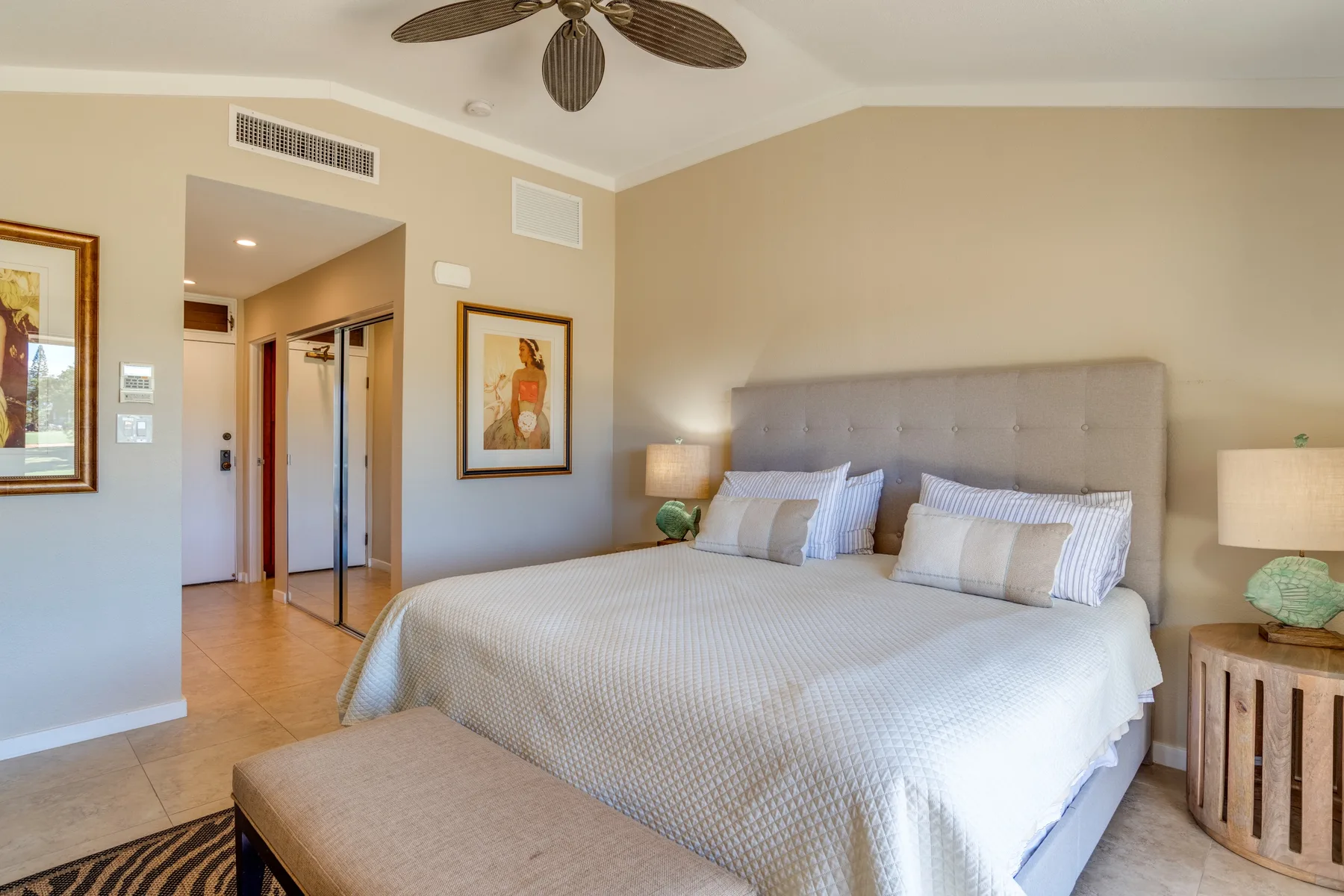 Un dormitorio con una cama grande, mesitas de noche y un ventilador de techo.