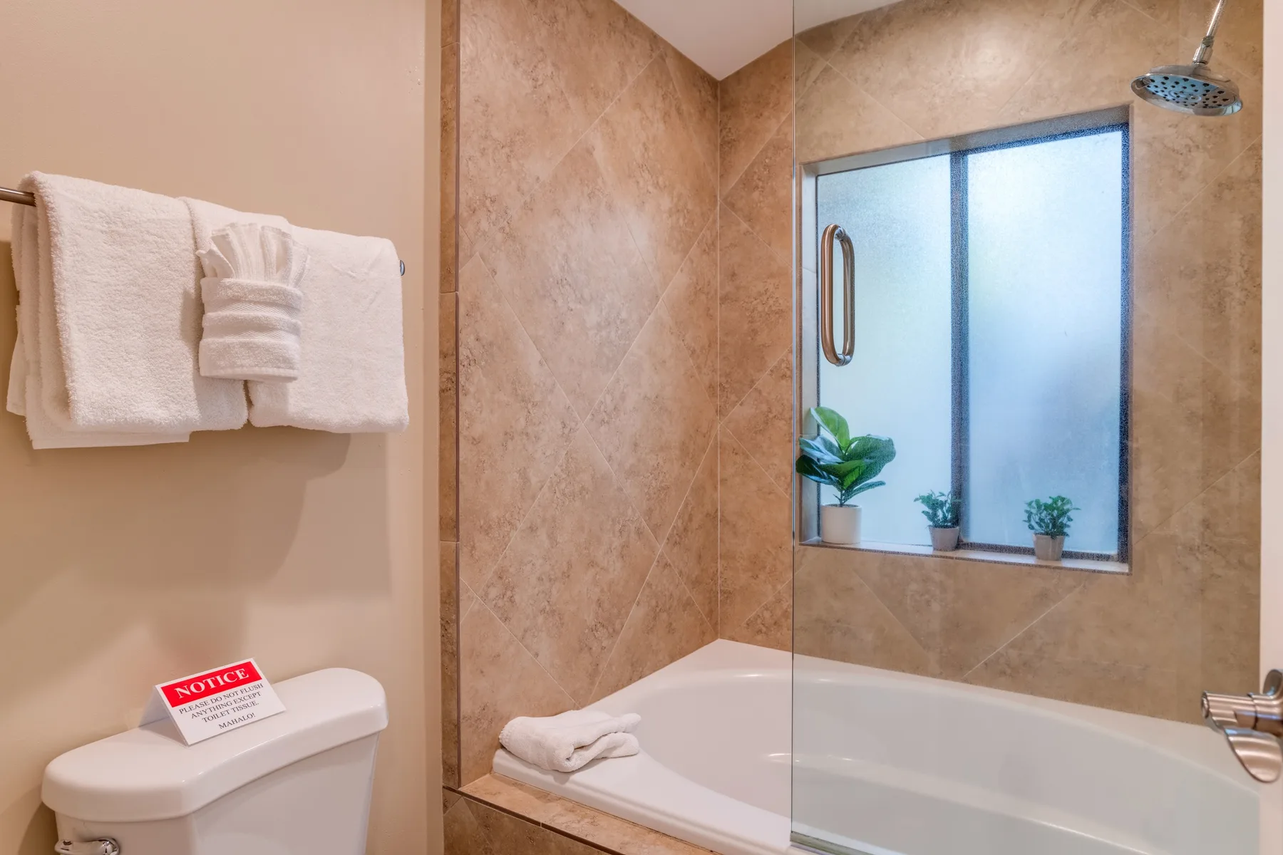 Un baño con bañera, ducha y toallas colgadas en la pared.