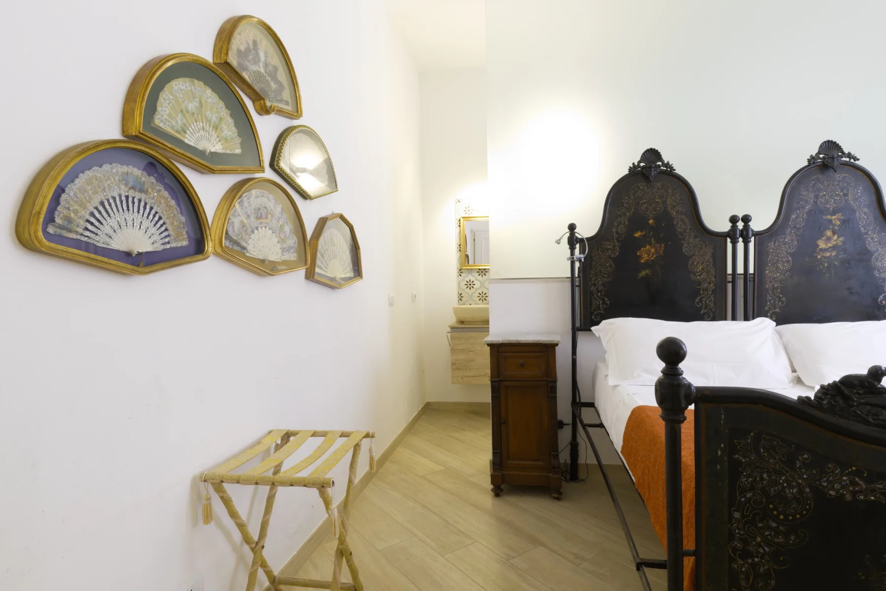 A bedroom with ornate dark headboards and decorative fans displayed on the wall.