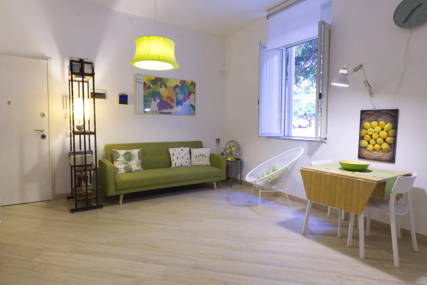 Una sala luminosa con un sofá verde y una mesa de comedor junto a la ventana.