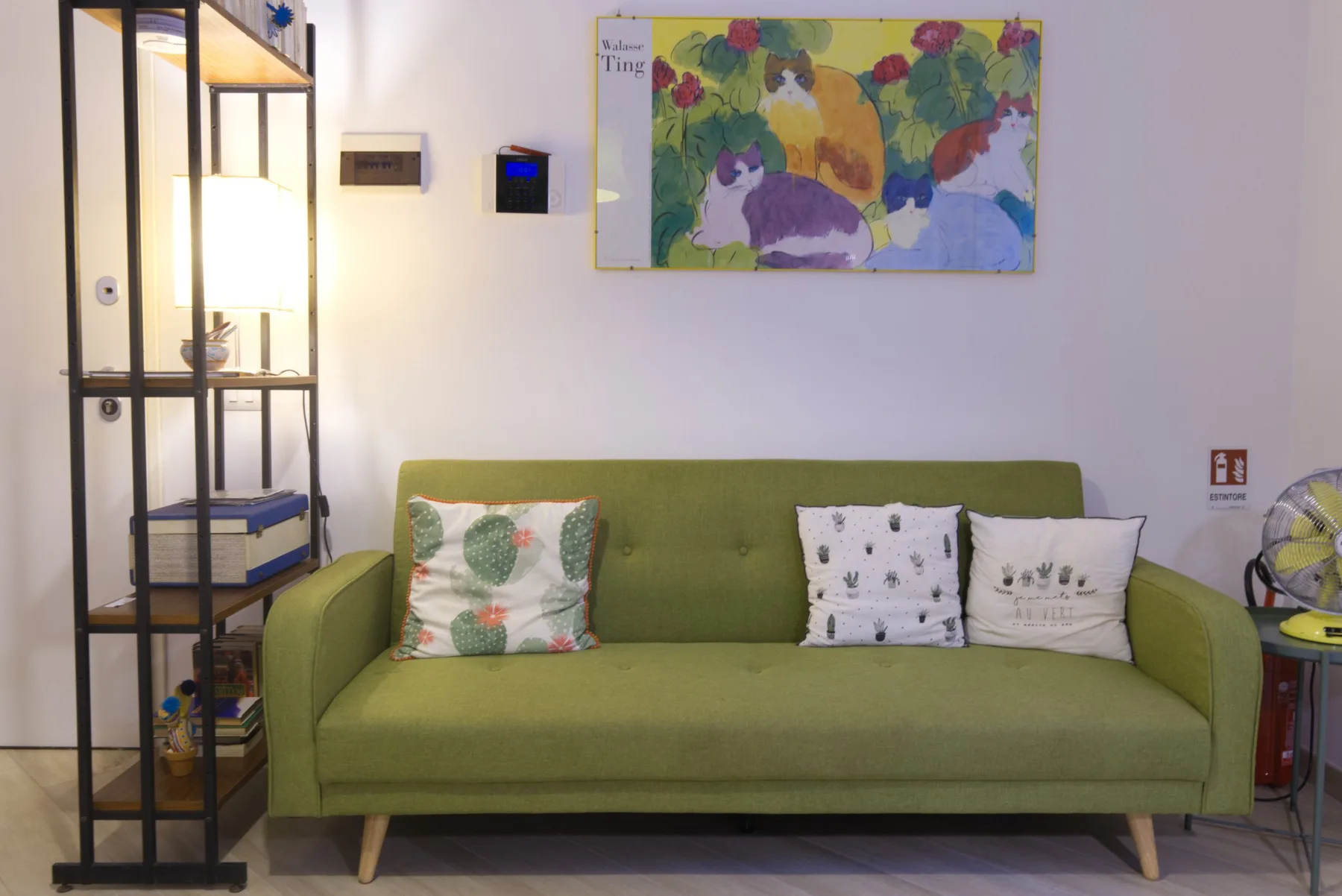 A green sofa sits beneath a colorful painting in a living room.