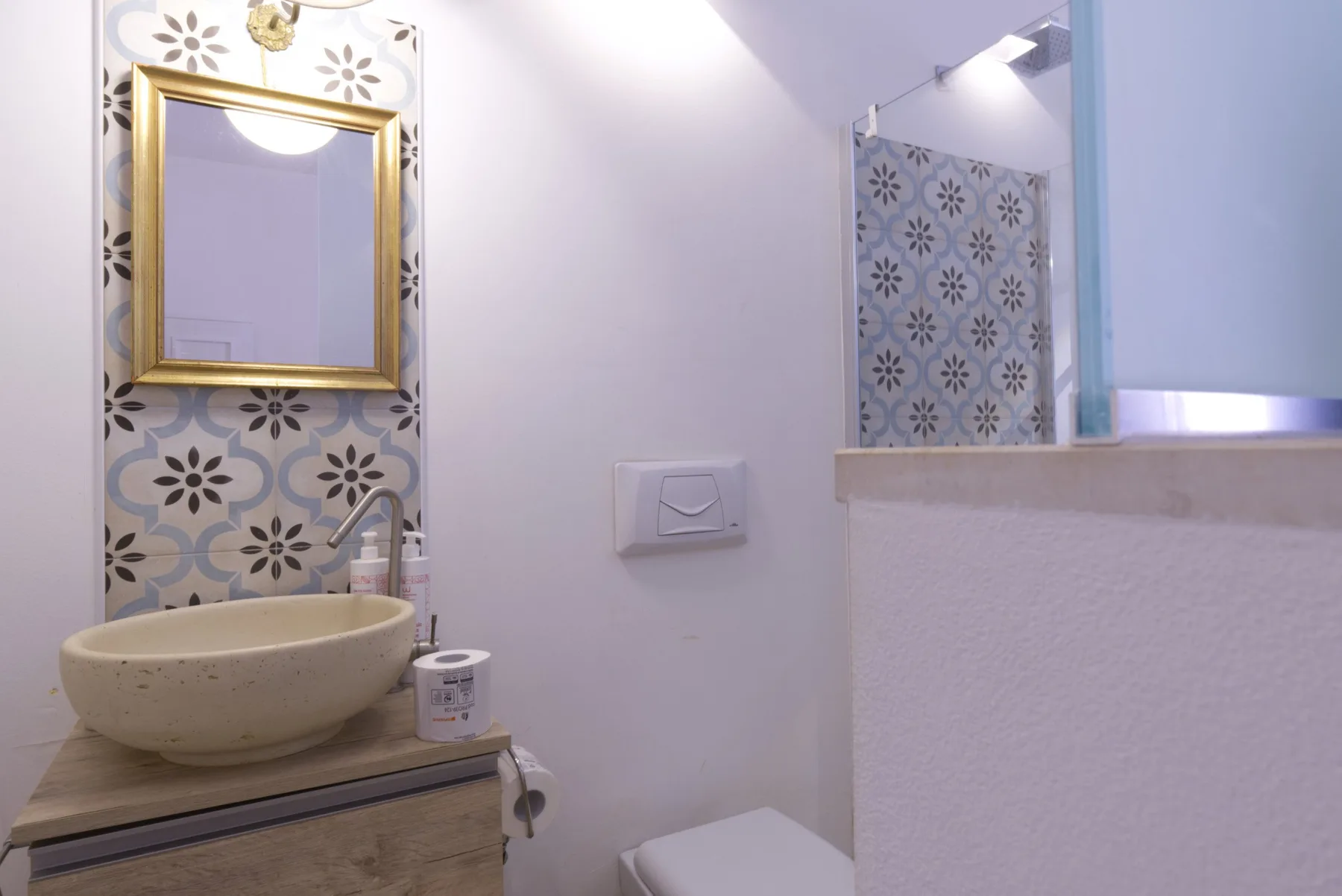 A bathroom vanity with a vessel sink and patterned tile behind it.