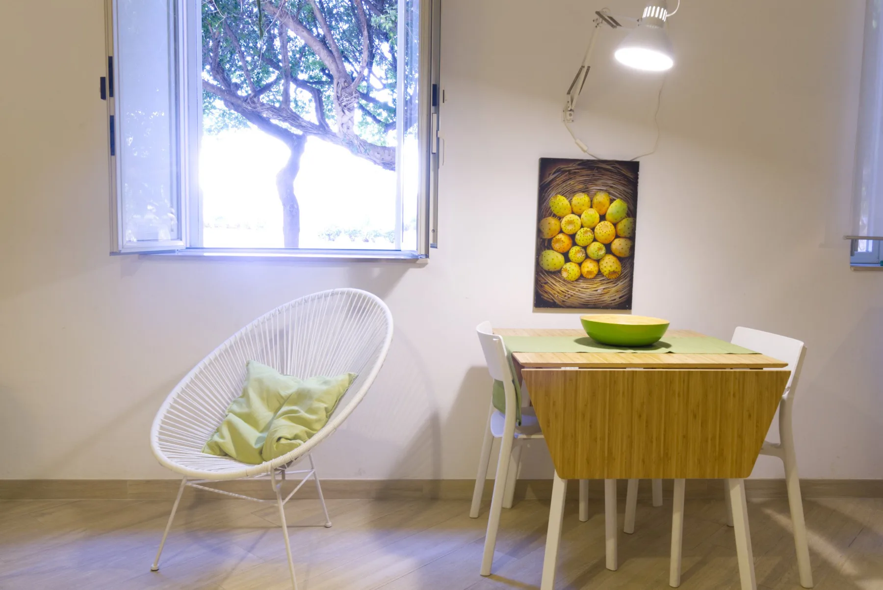 Un comedor con una mesa de madera, asientos blancos y una ventana amplia.