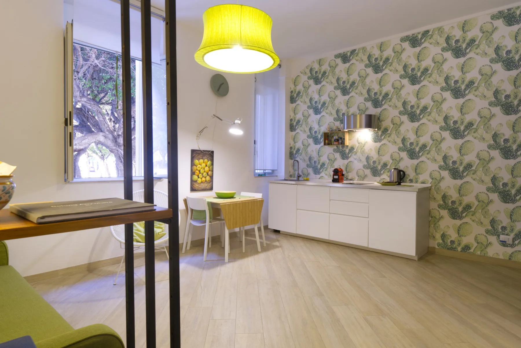 Un comedor luminoso con una mesa junto a una cocina compacta y papel tapiz estampado.