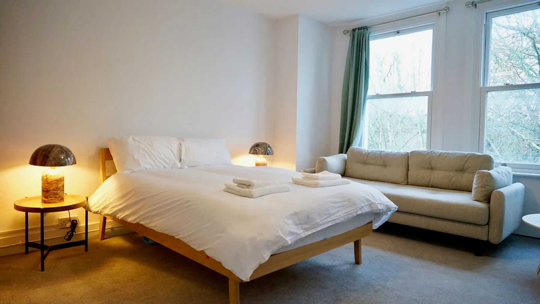 A bedroom with a bed and seating beside large windows.