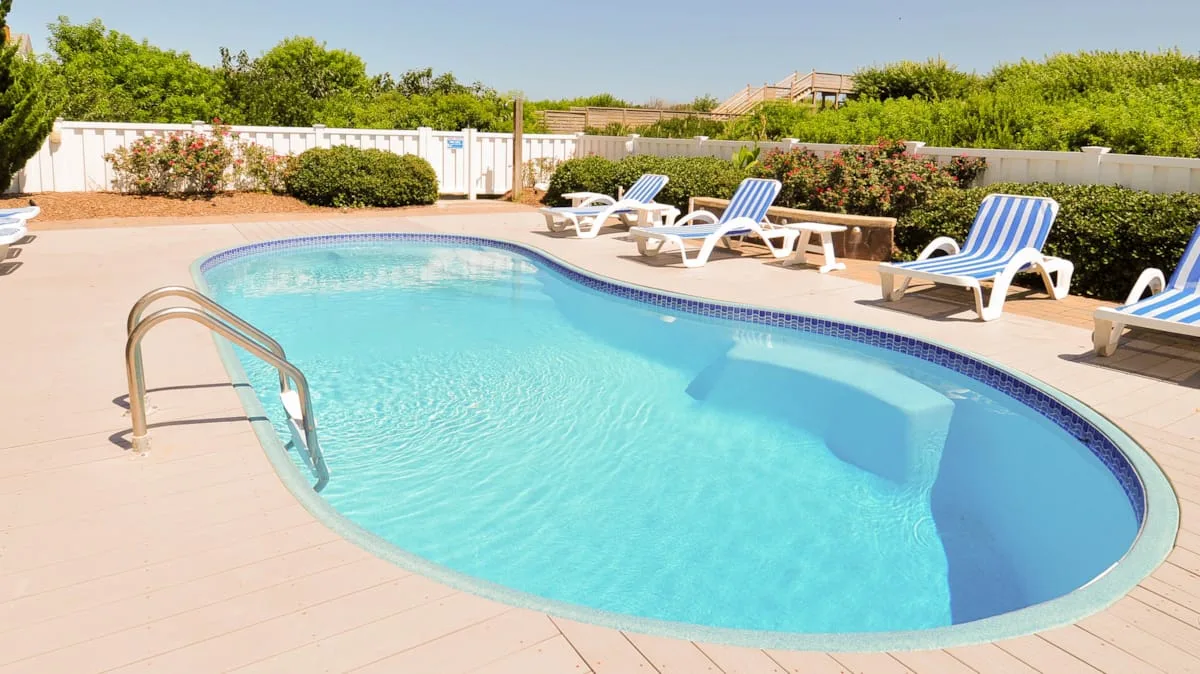 Una piscina con tumbonas en el patio que la rodea.