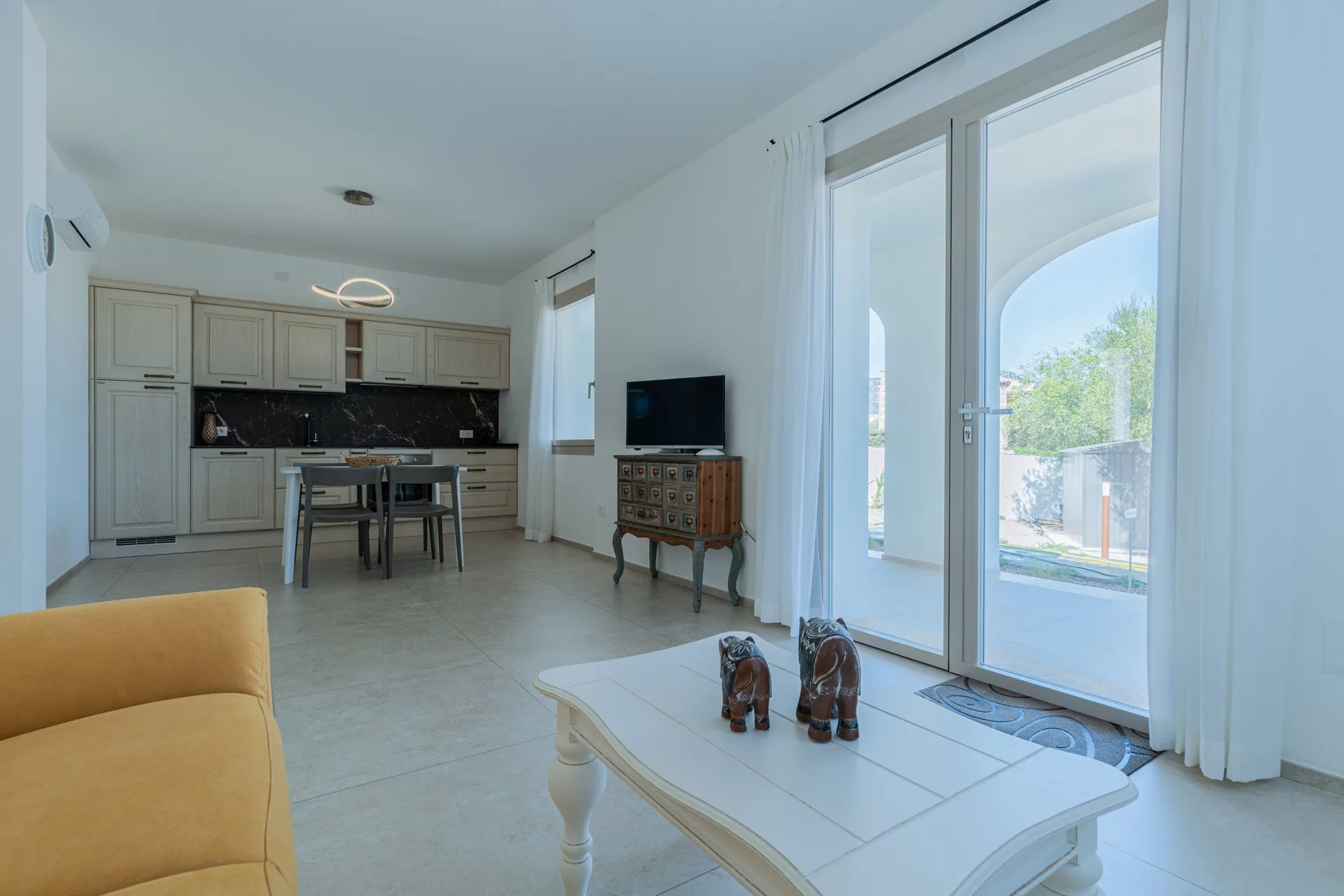 Una luminosa sala-comedor diáfana con cocina y grandes puertas de vidrio.
