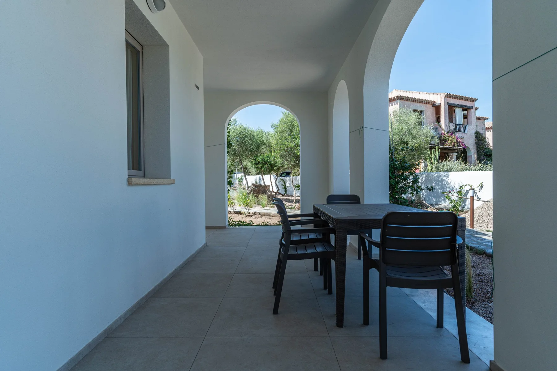 Un patio cubierto con una mesa de comedor y sillas junto a grandes arcos.