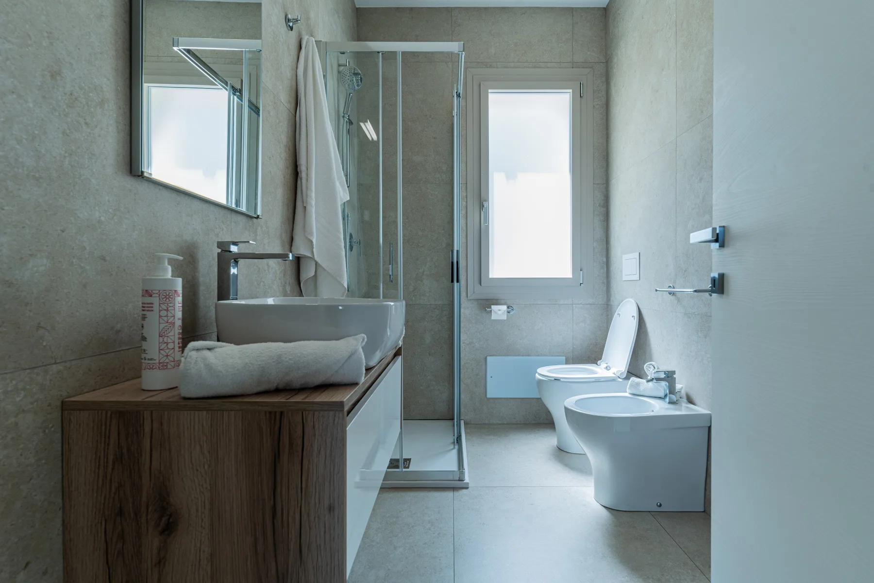 Un baño moderno con ducha de vidrio, lavabo, inodoro y bidé.