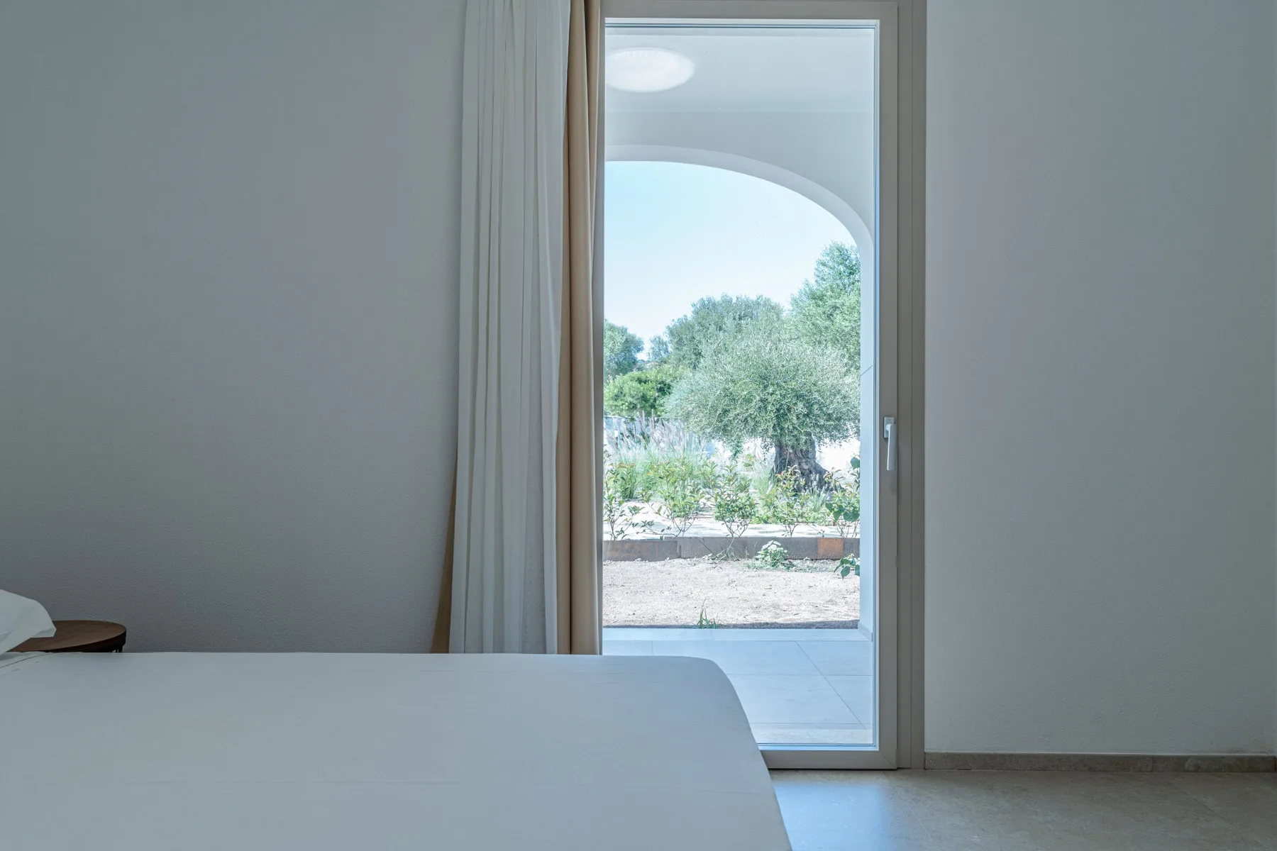 Un dormitorio con una cama junto a una puerta de cristal que da a un jardín.
