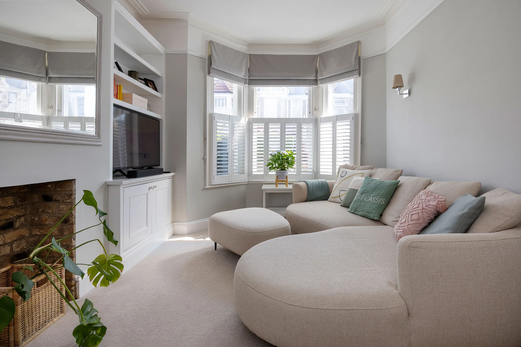 A bright living room with a curved sectional sofa and windows overlooking the street.