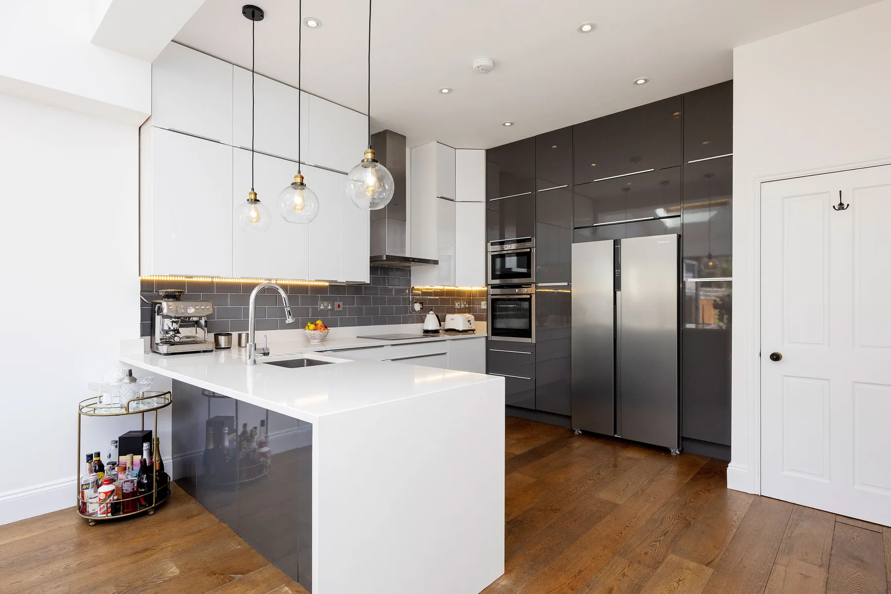 A modern kitchen with white cabinets, dark cabinetry, and a large island.