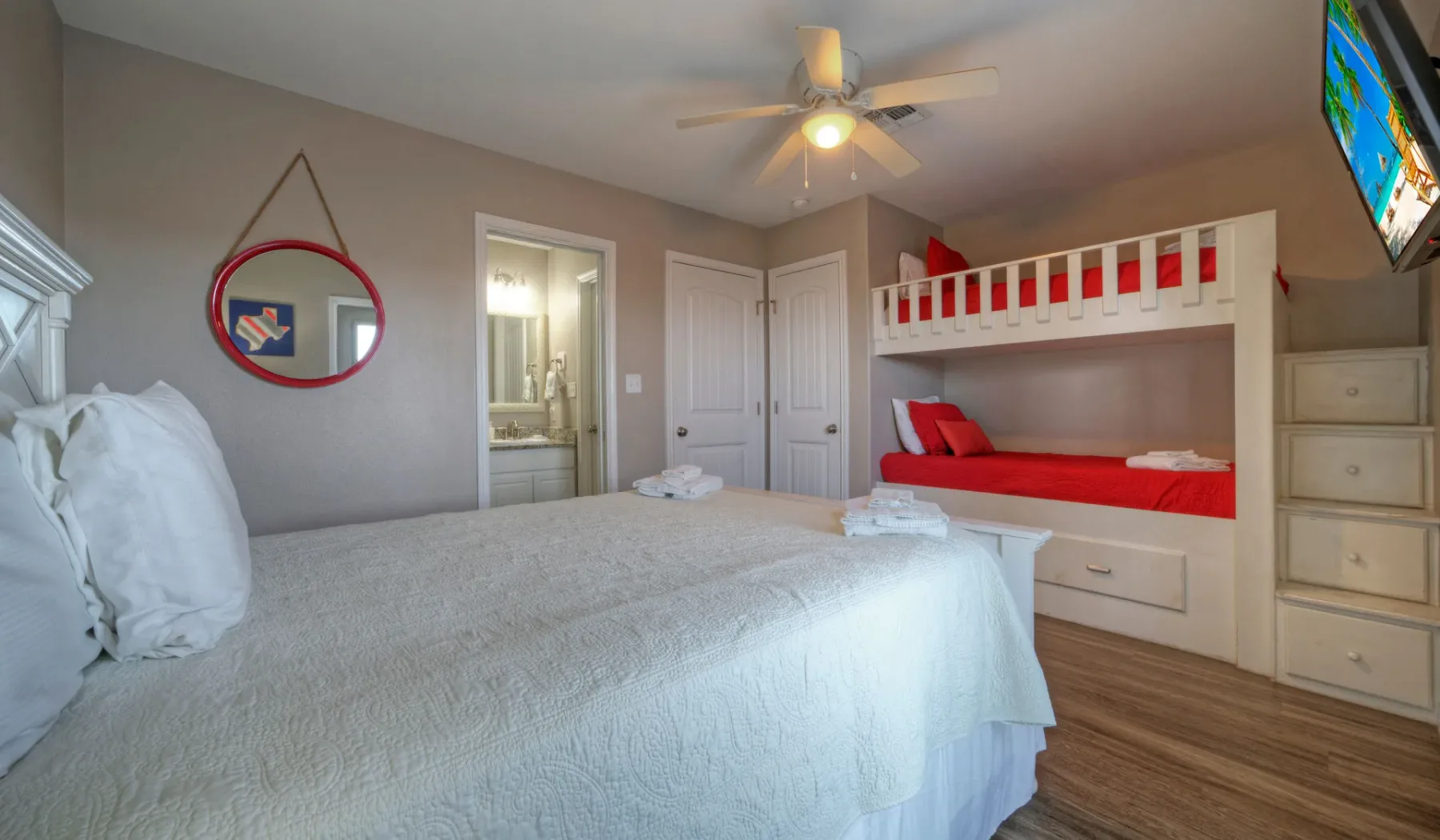 Un dormitorio con una cama grande y una litera roja junto a la pared.