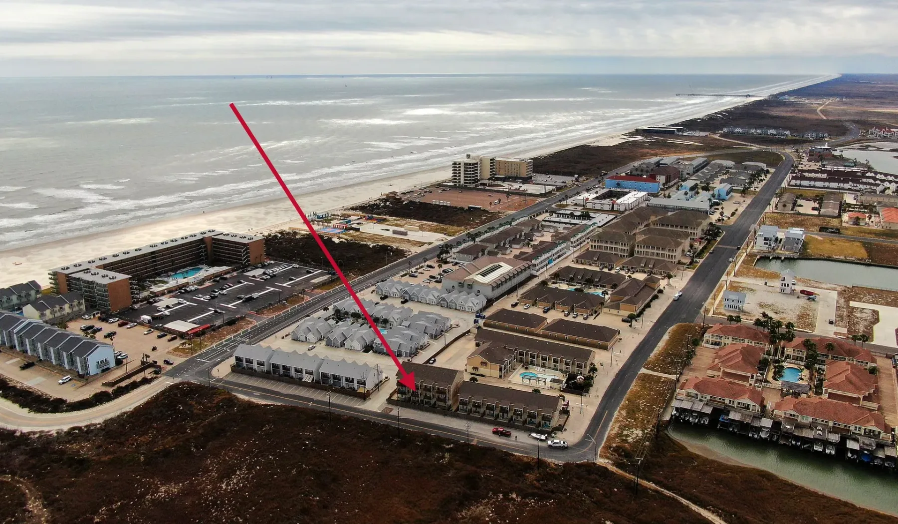 Vista aérea de edificios costeros junto a una amplia playa y el océano.