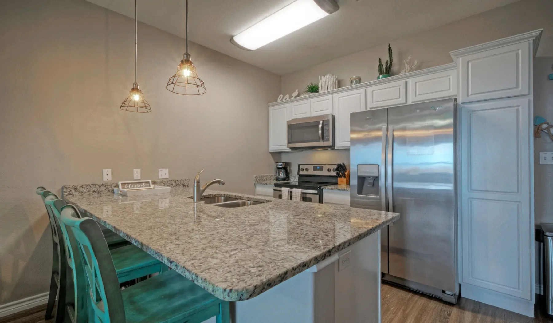 Una cocina con una isla grande de patrón pétreo y electrodomésticos de acero inoxidable.