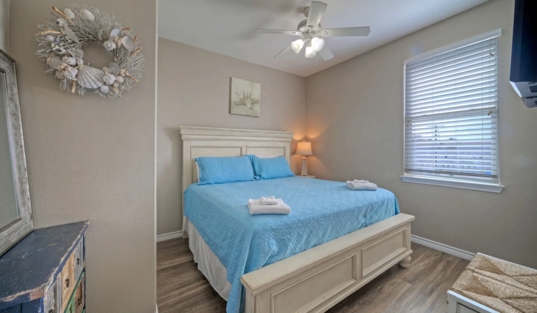 Un dormitorio con una cama vestida con ropa de cama azul y una ventana con persianas.
