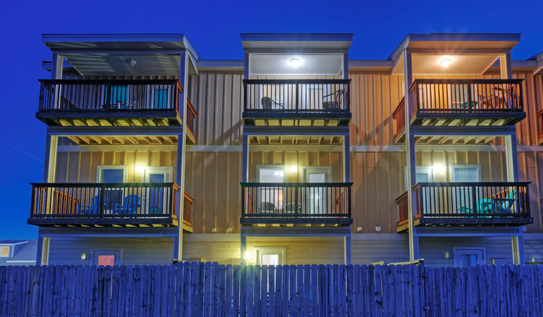 Una fila de viviendas de varios niveles con balcones está iluminada al anochecer.