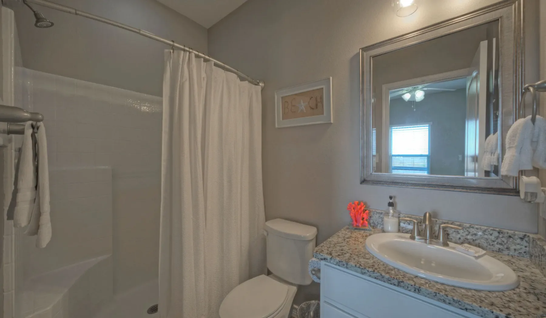 Un baño con una ducha con cortina y un lavabo bajo un espejo grande.