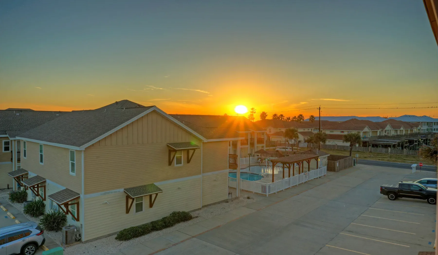 Edificios residenciales y una zona de estacionamiento bajo un atardecer brillante.