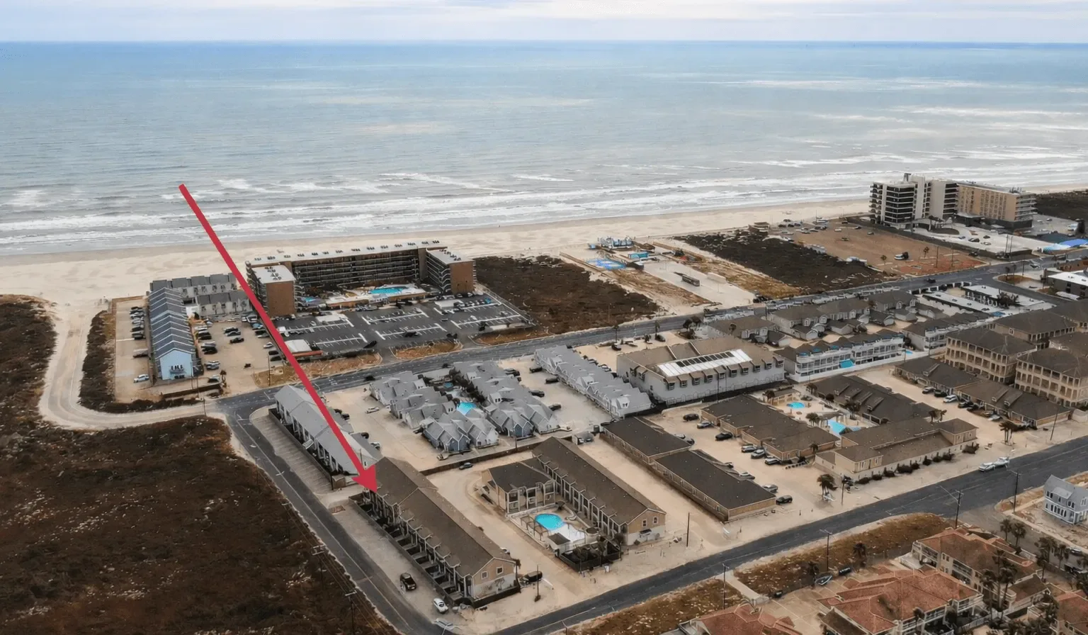 Vista aérea de un complejo turístico costero con edificios junto a la playa.