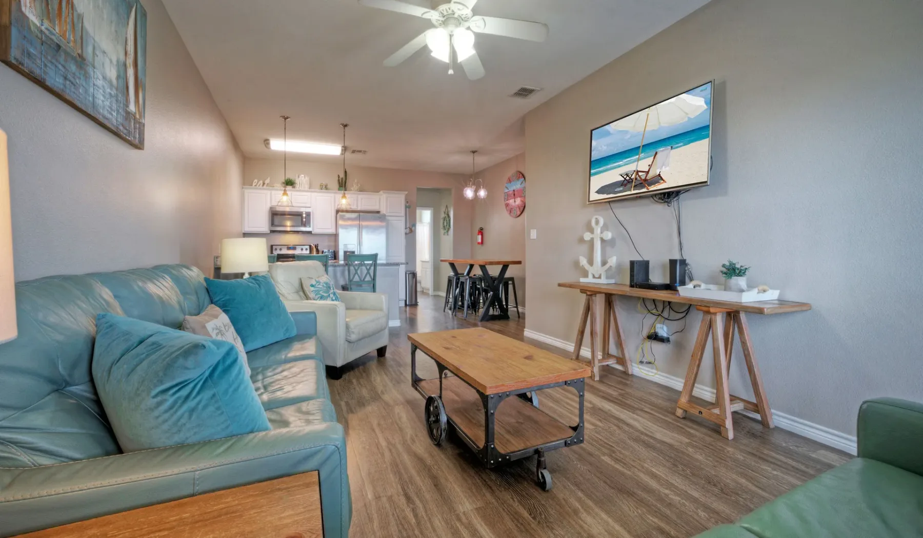 Una sala de estar con asientos azules, una mesa de centro y un televisor.