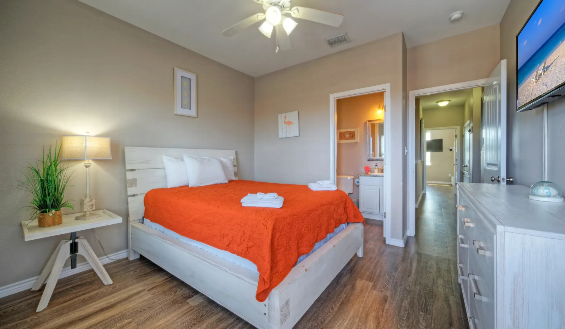 Un dormitorio con una cama cubierta con una colcha naranja brillante.