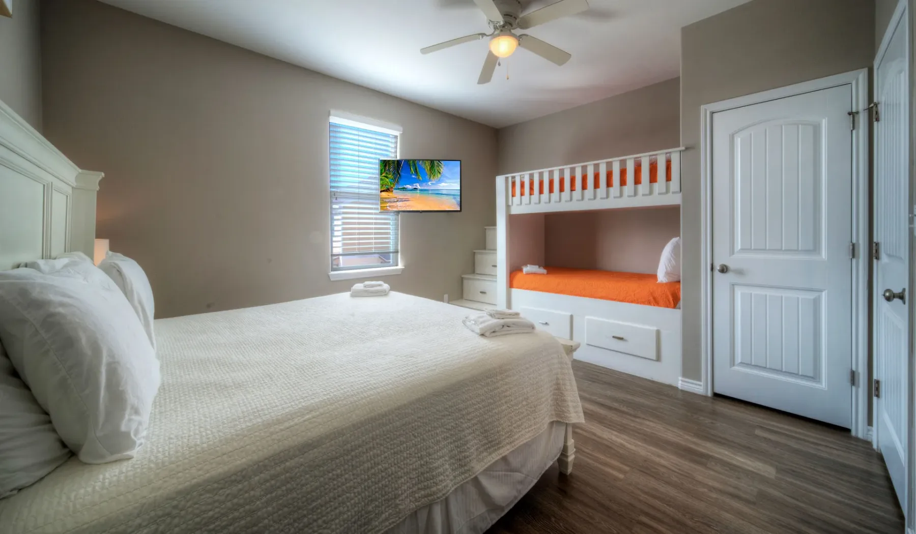 Un dormitorio con una cama grande y literas empotradas junto a una ventana.