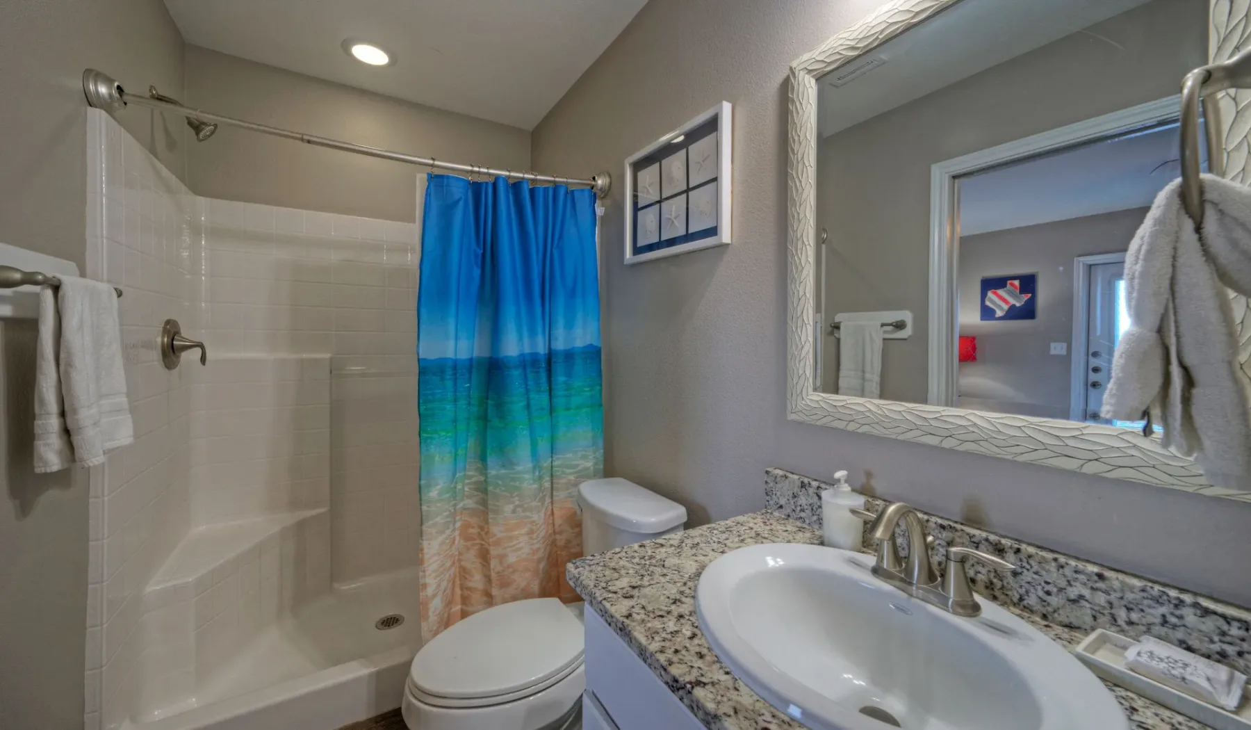 Un baño con lavabo, inodoro y bañera detrás de una cortina de ducha colorida.