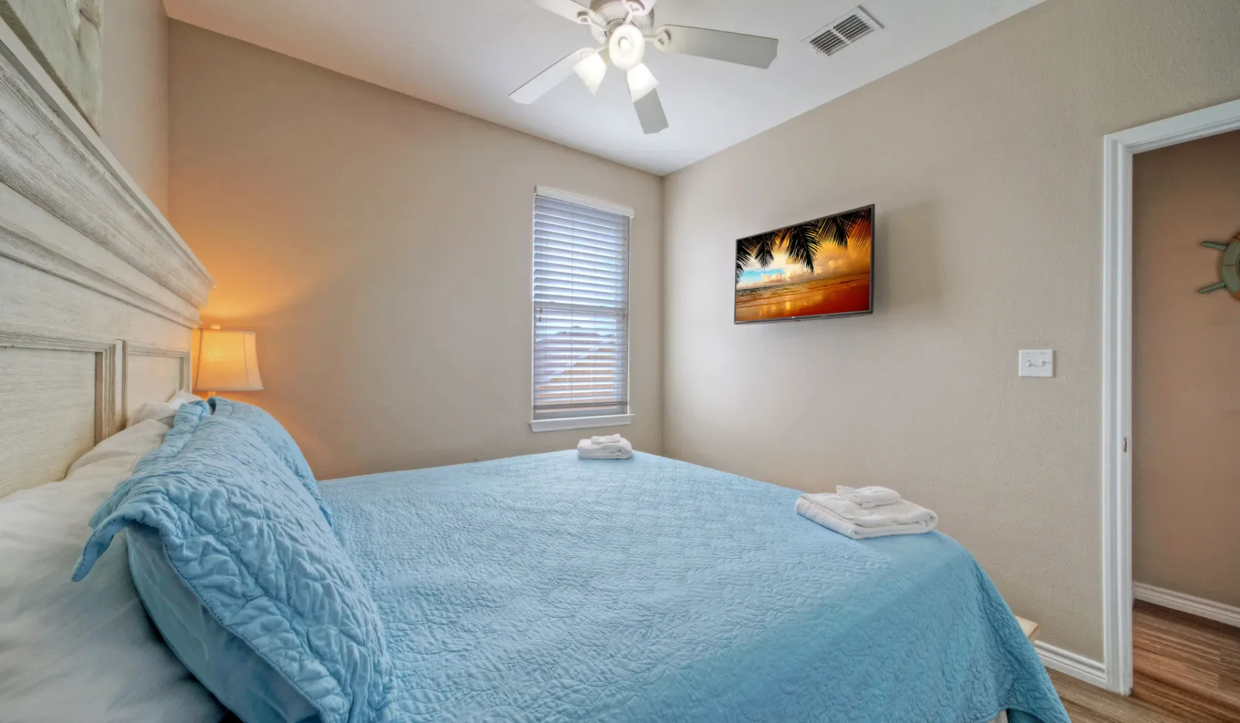 Un dormitorio con una cama cubierta de ropa de cama azul y un ventilador de techo.