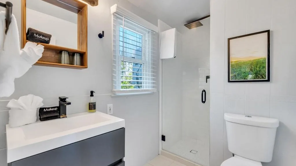 Un baño luminoso con lavabo, ducha e inodoro.