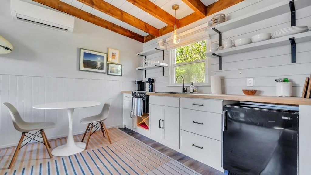 A bright kitchen with white cabinets, a countertop, and a small dining table.