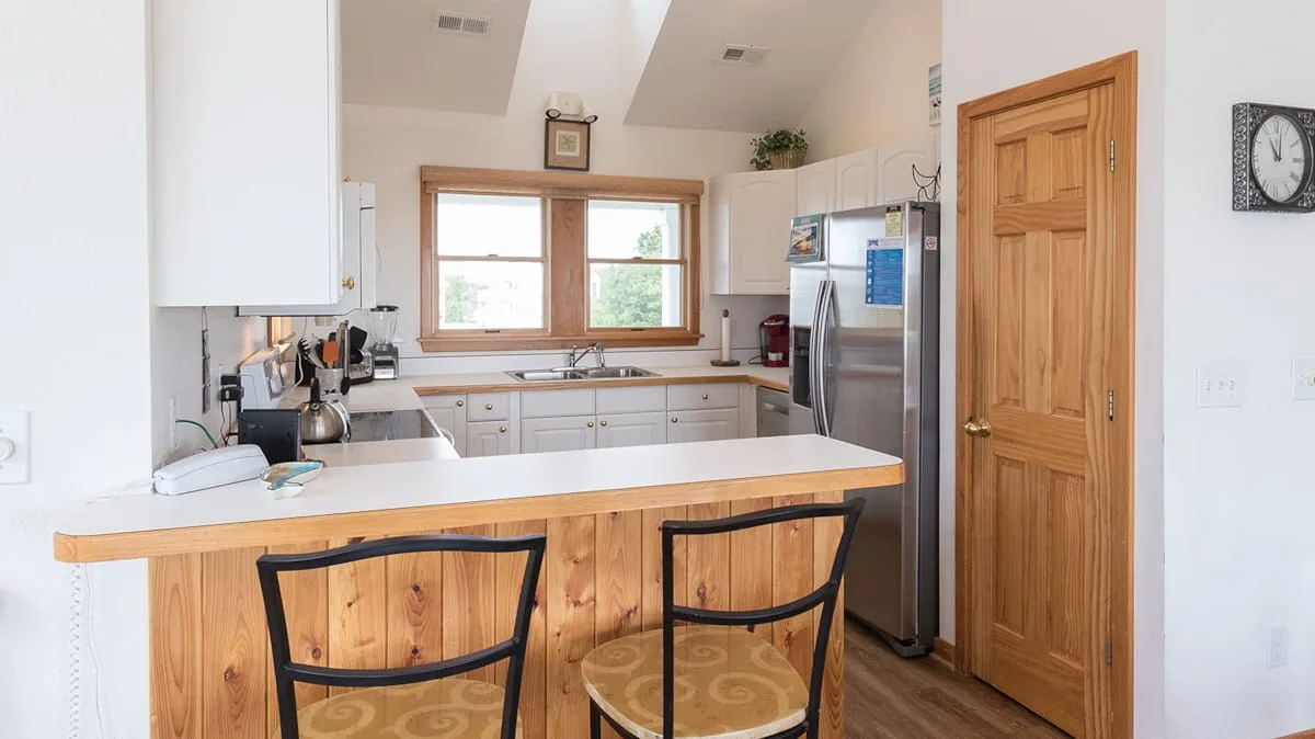 Una cocina luminosa con una isla de frente de madera y una ventana sobre el fregadero.